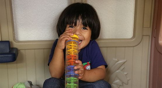 A young boy laughs as he plays with a toy at a Bright Space
